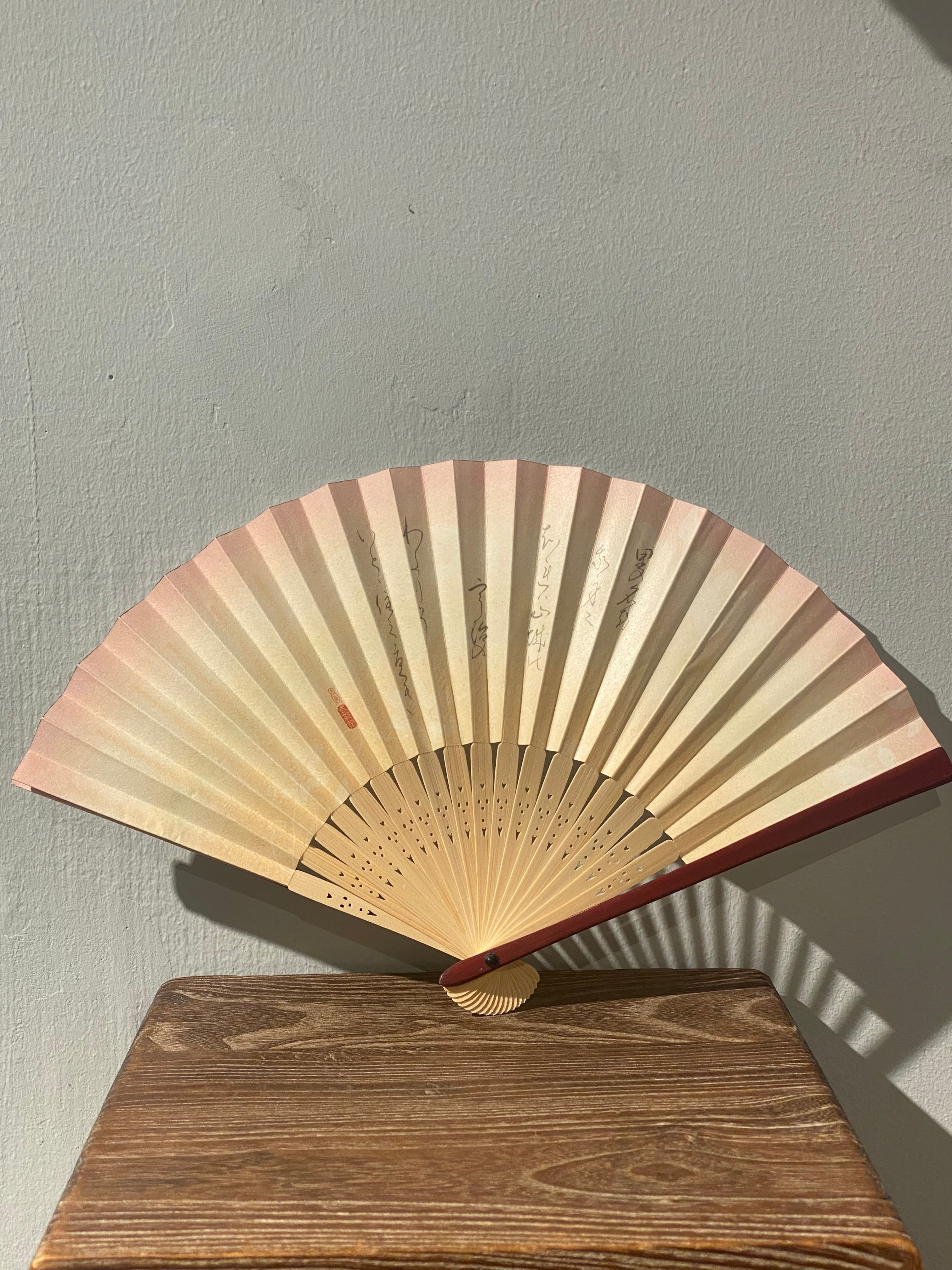 Unique fan with pink border and Japanese characters.